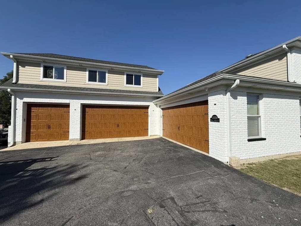 Exterior painting by Slaviks Painting & Decorating in Wood Dale, IL. The image shows a light home with stained wood garage doors.