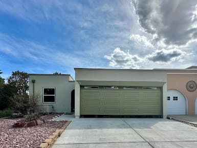 Exterior painting by All Painting Plus 2, LLC in Colorado Springs, Colorado. The image shows light walls around a green garage door.