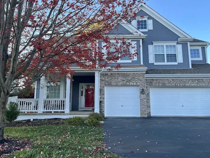 Exterior painting by CertaPro Painters of Columbus OH in Columbus, OH. The image shows blue two-story house with white porch and garage.