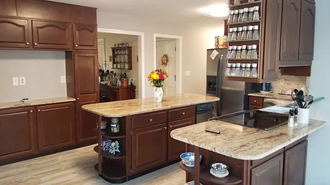 This is an image from WM Painting & More, located in Massachusetts. The photo shows a modern kitchen with dark wood cabinets, granite countertops, a center island, and stainless steel appliances.