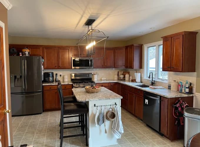 This is an image from CertaPro Painters of WNY, located in New York. The kitchen features dark wood cabinets, granite countertops, and stainless steel appliances.