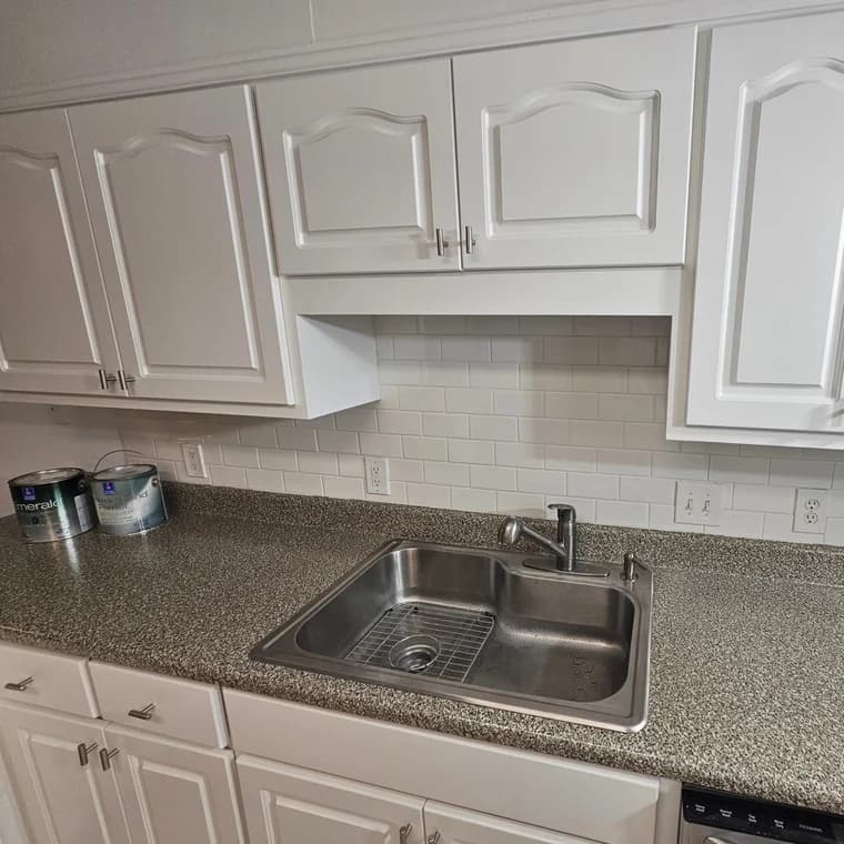 This is an image from Frank Fast Painter company, located in Panama City Beach, FL. The image is a modern kitchen with freshly painted white cabinets, granite countertop, and stainless steel sink