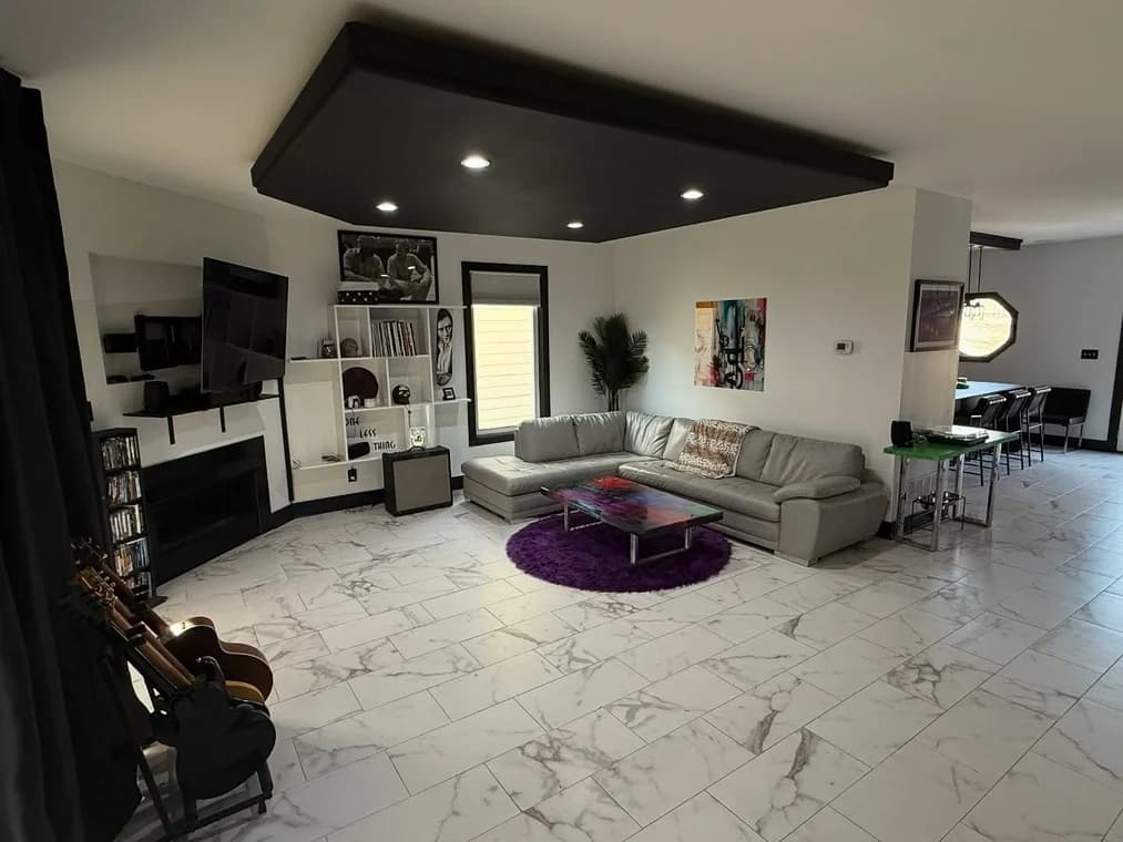 This is an image from Snap Painting Plus, located in Kentucky. The image shows a professionally painted living room with light walls, dark ceiling accents, modern lighting, and a clean open-concept layout.