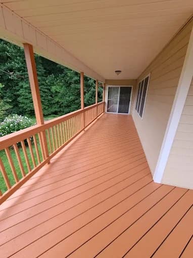 Deck staining project by Pro Painting & Drywall LLC in East Flat Rock, NC. The image shows a covered porch with peach decking, railings, and green posts.