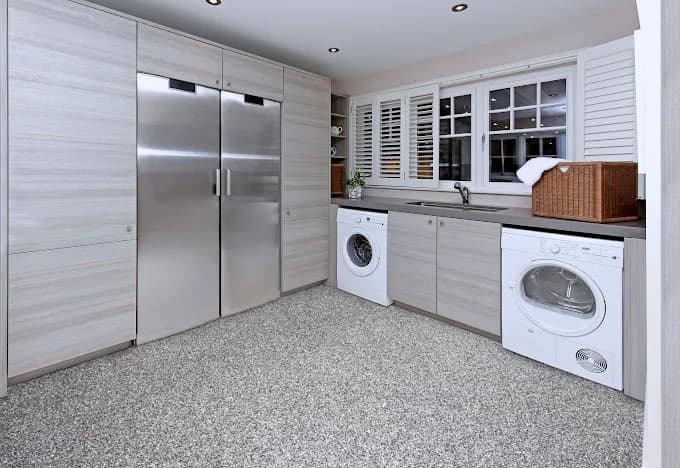 Interior painting project by Anderson Painting in Raleigh, North Carolina. The image shows a laundry room with cabinets, appliances, and speckled floor.