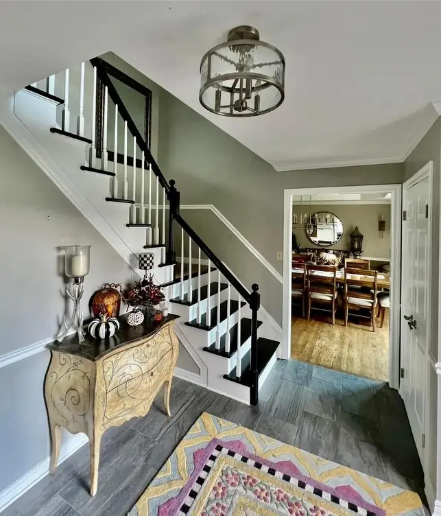 This is an image from R&R Painting & Concrete Coatings, located in New York. The entryway staircase has contrasting white risers and black treads with matching railing accents.