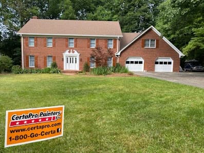 Exterior painting project by CertaPro Painters of Greensboro, NC in Greensboro, NC. The image shows a red brick home and lawn sign.
