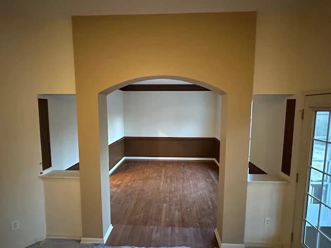 Interior painting project by 360° Painting of Gastonia Rock Hill, NC in Charlotte, NC. The image shows tan walls, white trim, an archway, and wood flooring.
