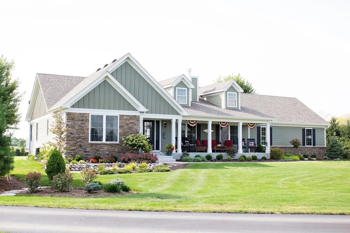 Exterior painting by Always Perfect Painters in St. Charles, Illinois. The image shows a stone-and-siding home with white trim and a green lawn.