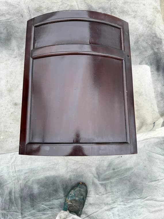 Dark brown stained kitchen cabinet door with a raised center panel and arched top.