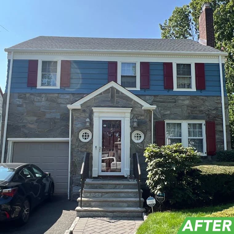 Front view of a stone-front house with blue siding, white trim, and red shutters, painted by Elite Painting and Power Washing, Inc.
