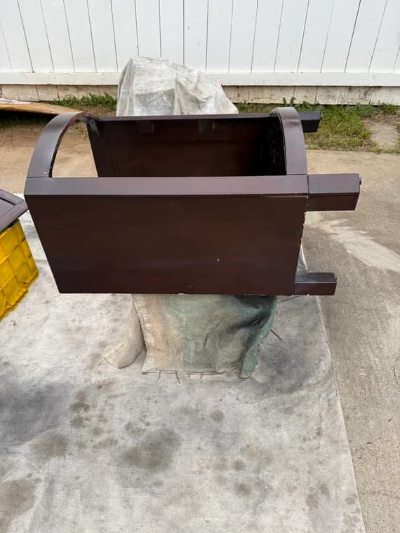 Dark wood vanity base coated with shellac during outdoor refinishing process