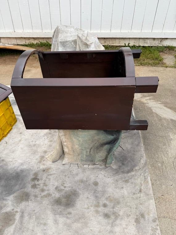 Dark wood vanity base coated with shellac during outdoor refinishing process