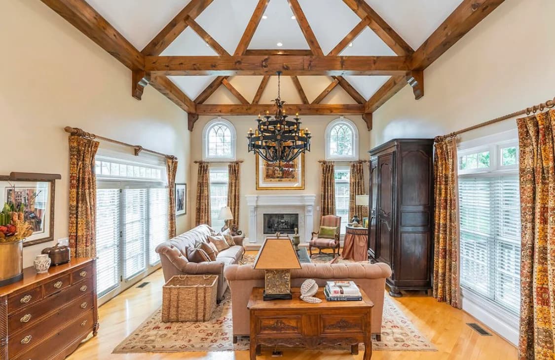 This is an image from Big J Painting LLC, located in Kentucky. The photo shows a living room with vaulted ceilings, exposed wood beams, and cream-colored painted walls for a warm, inviting look.