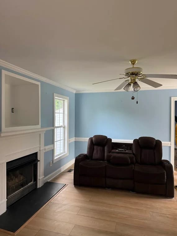 Interior painting project by CertaPro Painters of Clayton-Greenville, NC in Clayton, NC. The image shows a living room with blue walls, fireplace, and sofa.