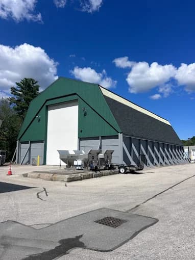 This is an image from CertaPro Painters of Attleboro, MA. It displays a large commercial building with a green roof and gray exterior walls under a bright blue sky.