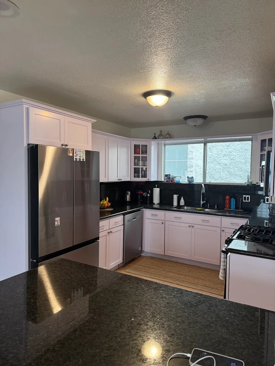 This is an image from ALLBRiGHT Painting, located in California. The image is from ALLBRiGHT Painting and shows interior painting in a kitchen with white cabinets, black countertops, stainless steel appliances, and overhead lighting.