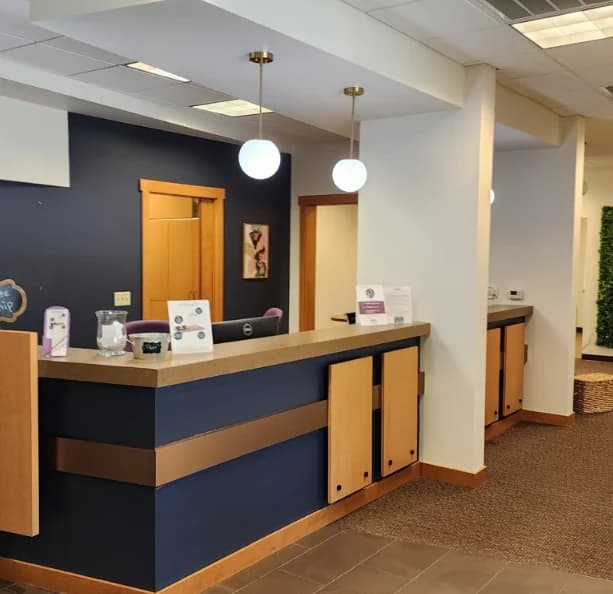 Interior painting project by Grady Jones Paint in Garner, NC. The image shows a reception counter, blue accent wall, wood doors, and pendant lights.