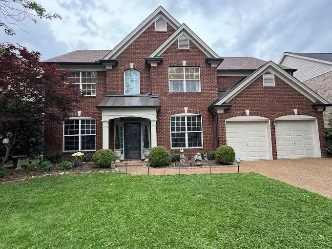 Painting work by Global Painting Pro LLC in Nashville, Tennessee. The image shows a brick house exterior with light trim.