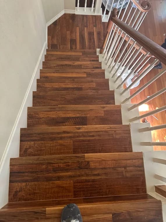 "This is an image from L&D Painting & Remodeling, located in Texas. The photo displays a wooden staircase with newly refinished steps and white railings."