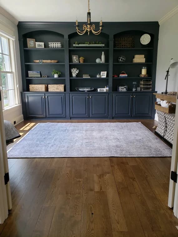 This is an image from Painting by Robertson, located in California. The image shows an interior custom-painted built-in shelving and cabinetry unit finished in a dark navy color with detailed trim work.