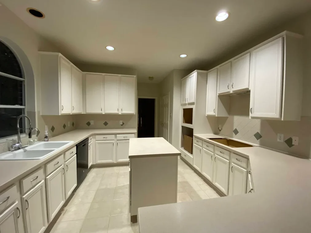 "This is an image from Lee House Paint & Repair, located in Texas. The kitchen features white painted cabinets, recessed lighting, and a spacious layout with an island."