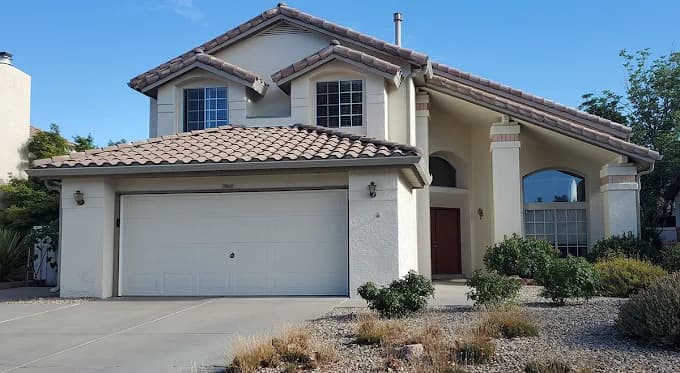 This is an image from CertaPro Painters of Albuquerque, located in New Mexico. The photo shows a freshly painted two-story stucco home with a light beige exterior, brown tiled roof, and clean white trim.
