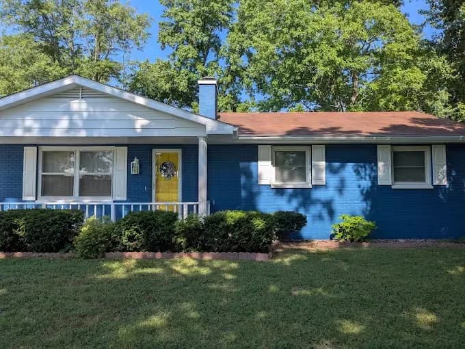 Painting by Men In White Painting LLC in Mt Vernon, IL. The image shows a blue-painted brick home exterior with white trim.
