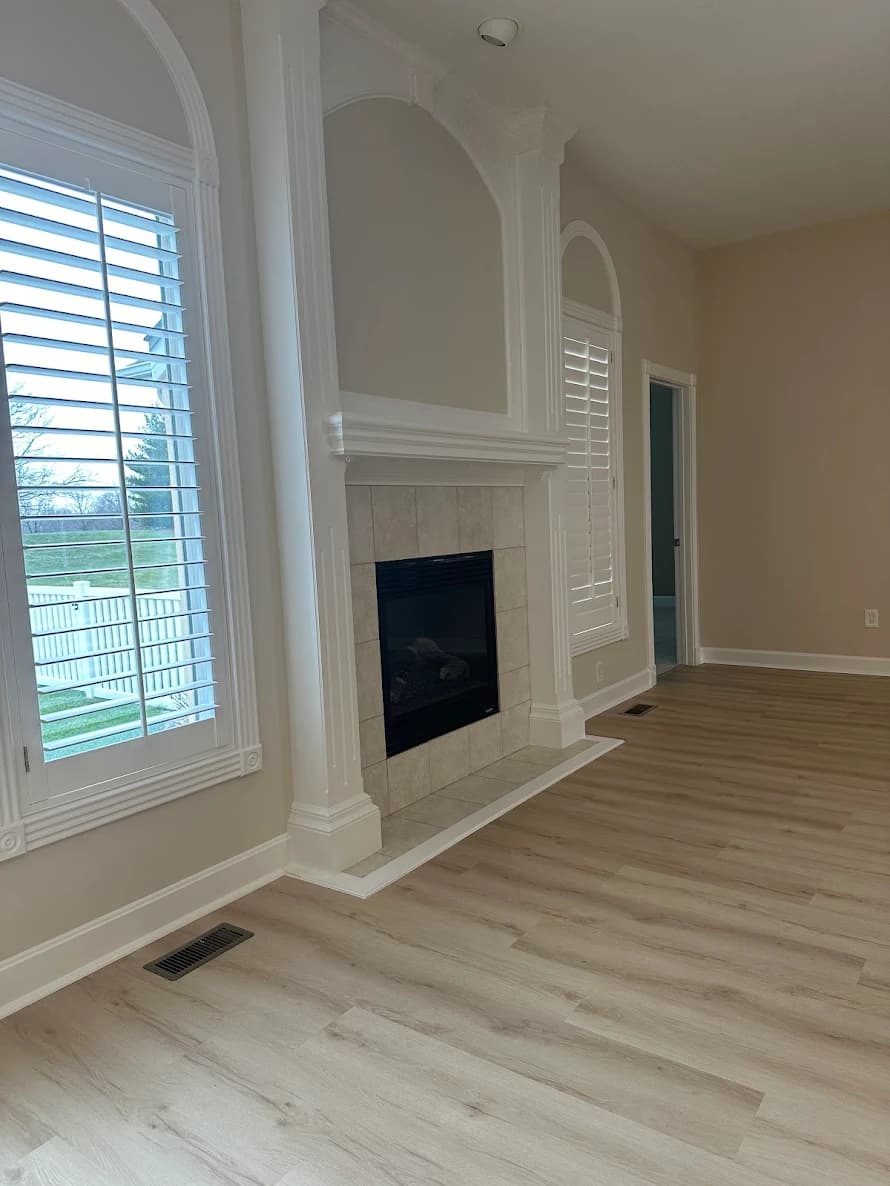 This is an image from KC Sharp Co. The image shows a living room with freshly painted white trim and built-ins around a fireplace.