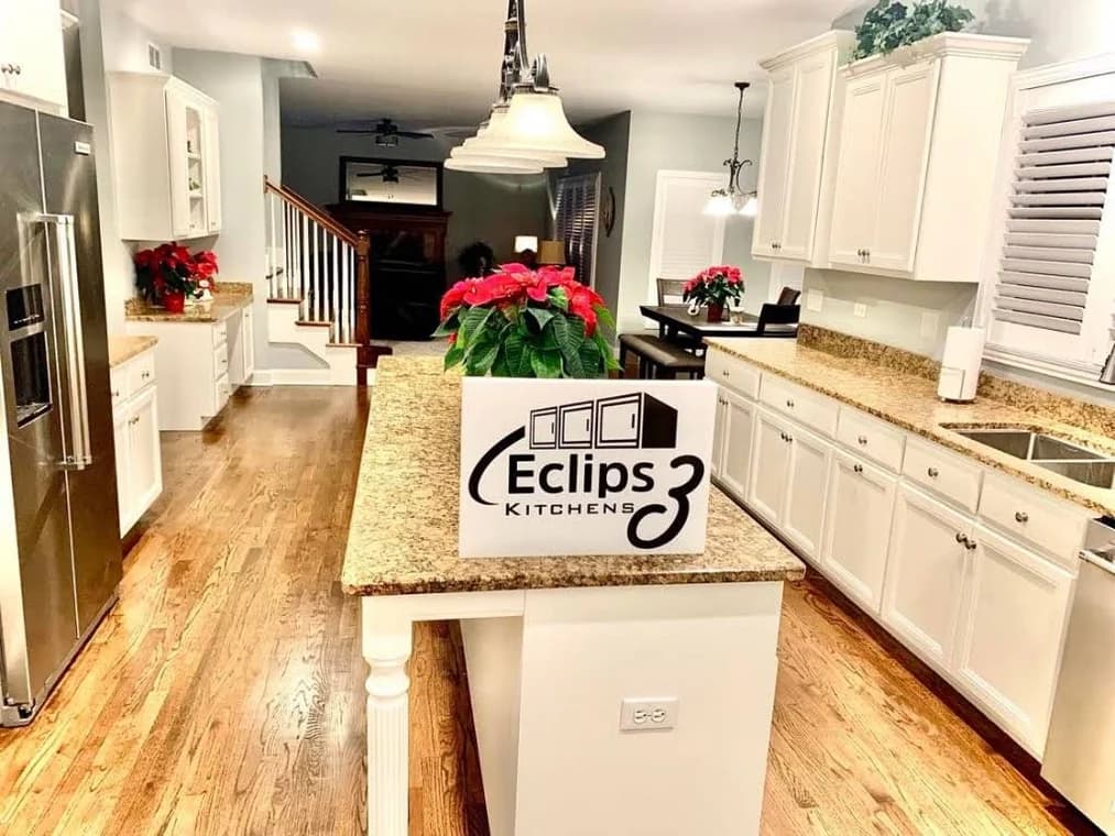 Kitchen cabinet refinishing by Eclips3 Kitchens LLC in Orland Park, IL. The image shows a white kitchen with granite island.