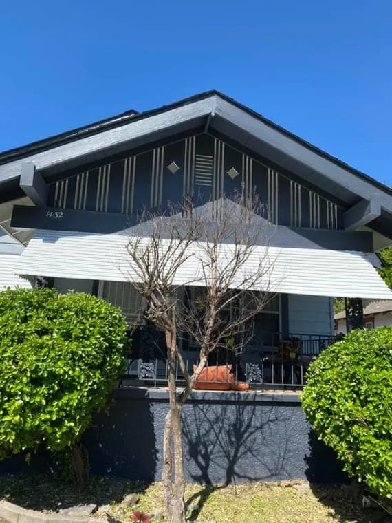 This is an image from Majestic Home Painting, featuring a house with dark gray and white exterior accents. The trim details and geometric design under the roofline give the home a bold, modern look.