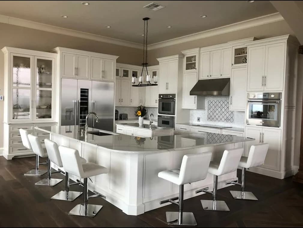 "This is an image from Texas Star Painting, located in Texas. The photo shows a large white luxury kitchen with an oversized island, sleek stainless-steel appliances, and white cabinetry."