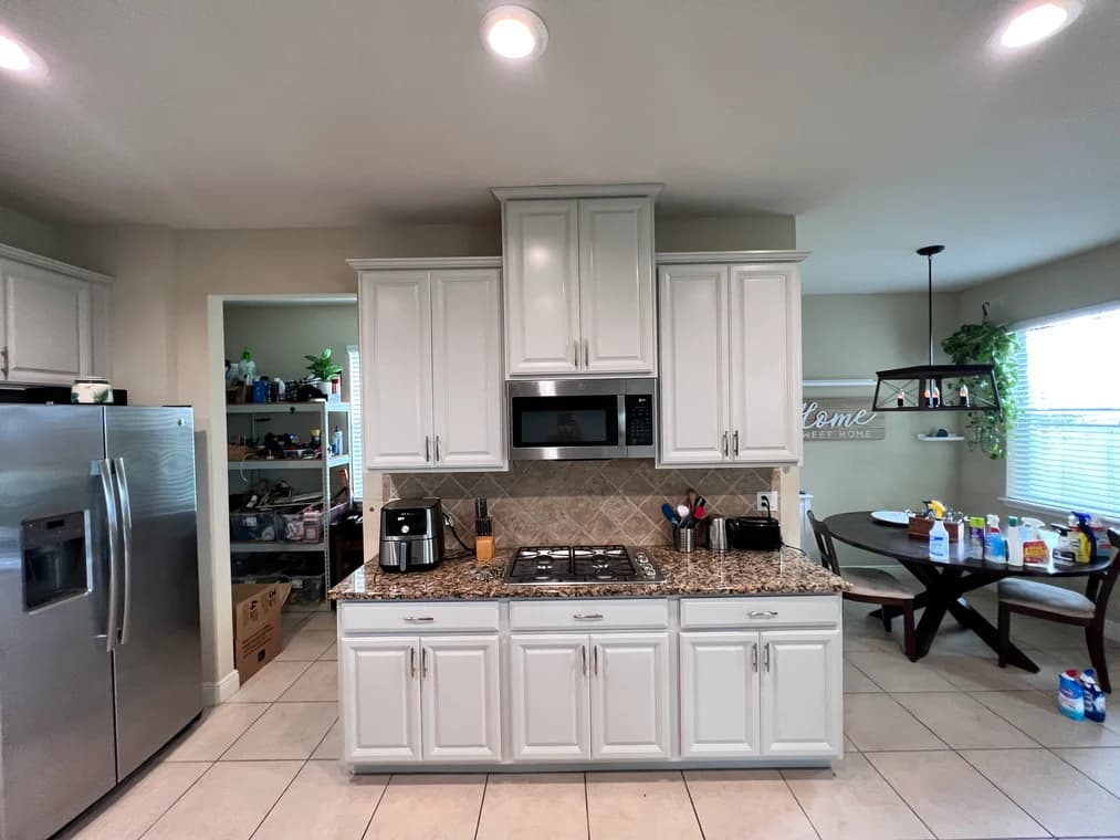 This is an image from Two Brothers Residential Maintenance & Service Corporation, located in Illinois. The kitchen photo shows freshly painted white cabinets with raised panel doors, silver hardware, granite countertops, and recessed lighting.