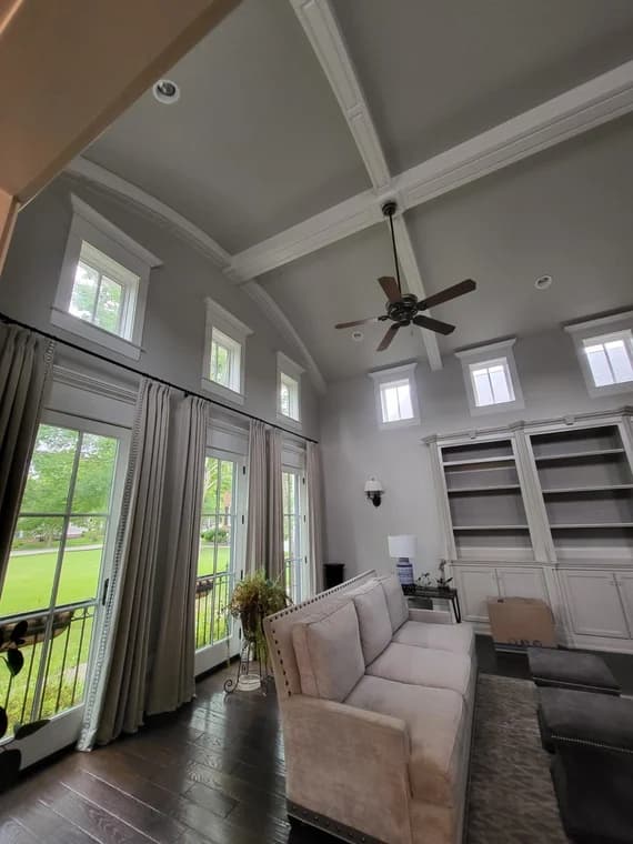 This is an image from Gomez Painting LLC, located in Kentucky. The interior living room features tall windows with white trim, light gray walls, a vaulted ceiling with beams, and a beige sofa.
