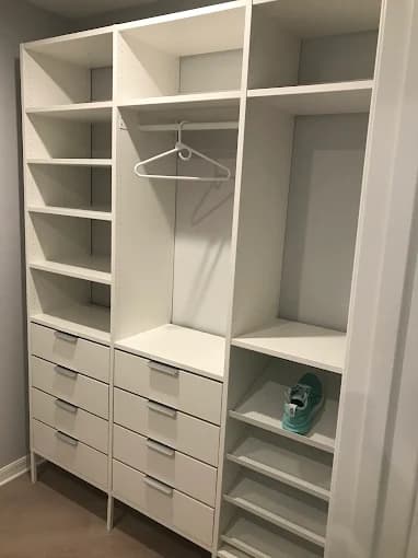 This is an image from Golden Hands Handymans company, located in Windermere, FL. The image is a custom white closet organizer with shelves, drawers, hanging space, and shoe racks installed in a walk-in closet