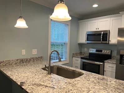 Kitchen painting by CertaPro Painters of Hickory in Hickory, NC. The image shows gray walls, white cabinets, granite counters, and pendant lights.