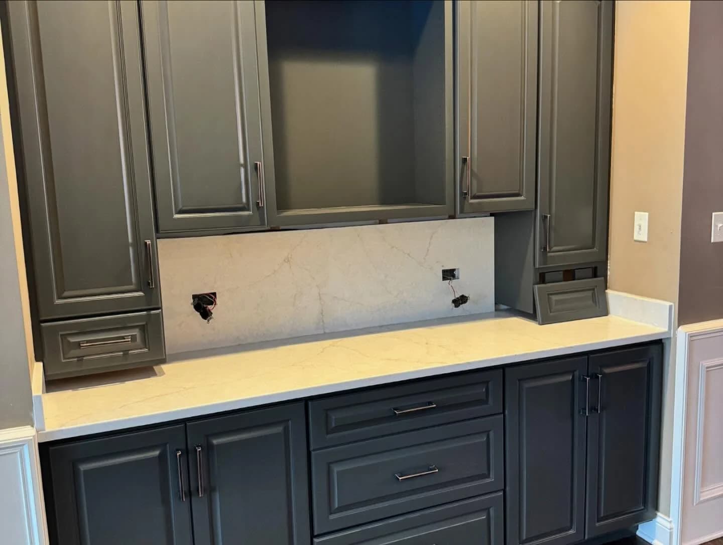 Cabinet painting by Tupelo Lane Designs in Naperville, Illinois. The image shows charcoal built-in cabinets, white counters, and a stone backsplash.