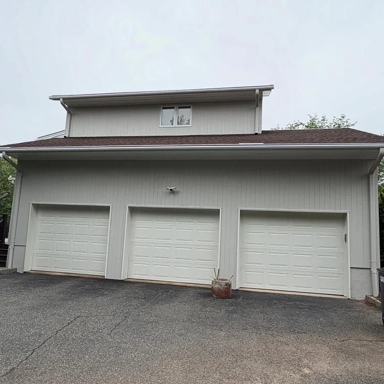 Three-car garage with clean white siding and matching trim, showcasing a crisp exterior painting update.