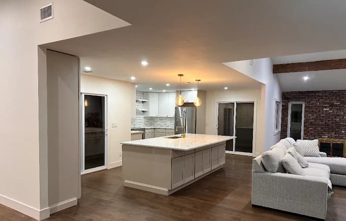 This is an image from Teall Painting, located in Michigan. The image shows a newly painted open-concept interior with a modern kitchen, white cabinetry, a large island, recessed lighting, and freshly finished walls.