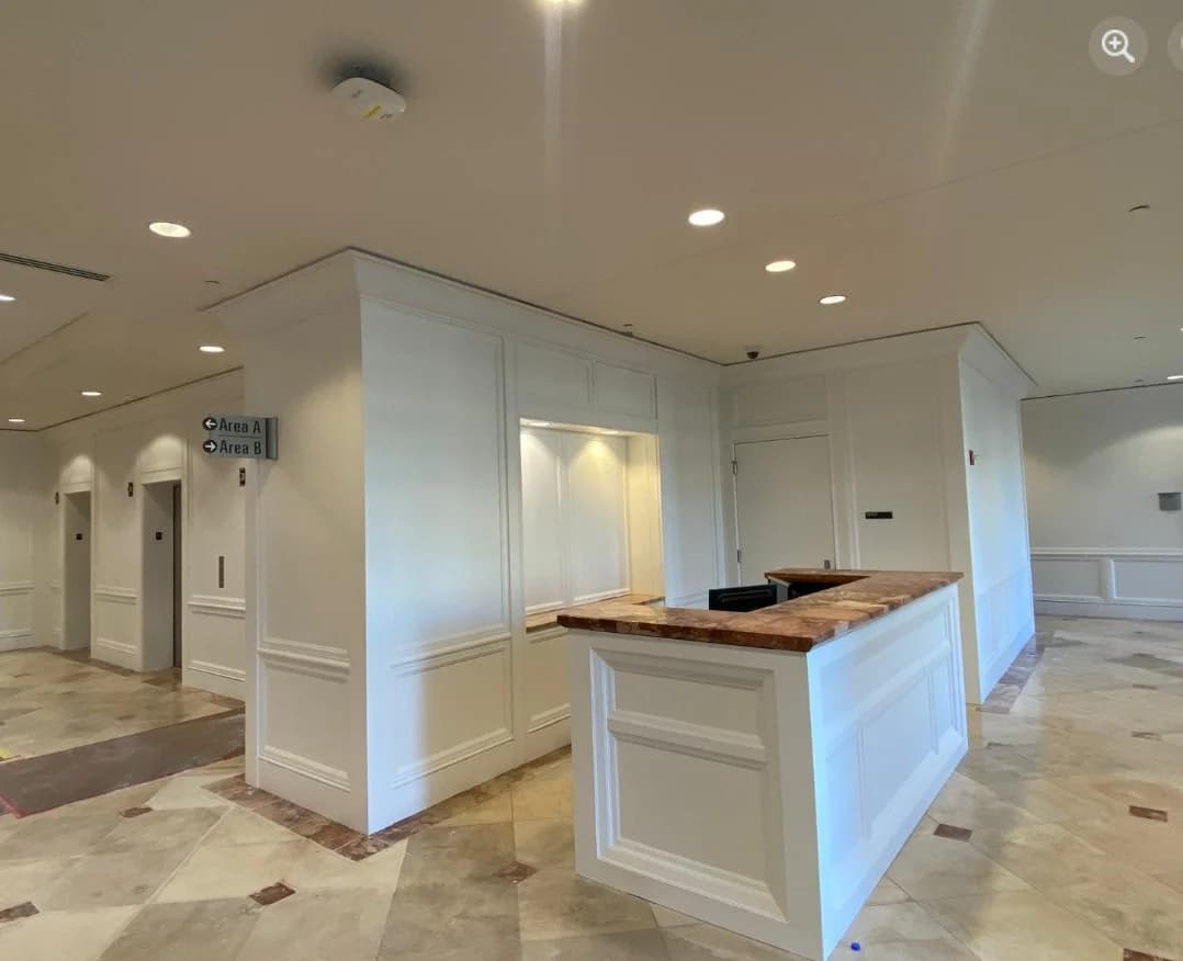 This is an image from CertaPro Painters of Shawnee Mission, KS. The image is a commercial lobby in Shawnee Mission KS with freshly painted white walls, paneled trim, and a reception desk.