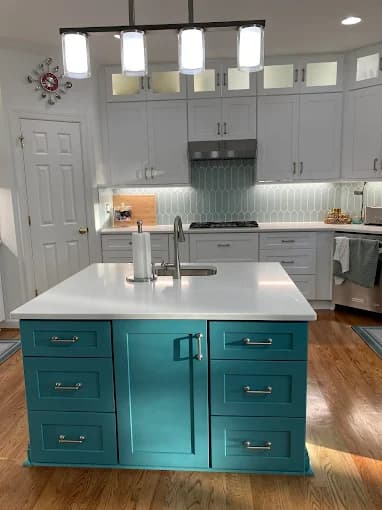 Cabinet painting project by CPM Painting INC in Raleigh, NC. The image shows a white kitchen with a teal island and wood flooring.