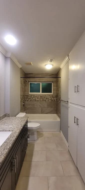 "This is an image from Perera Painting & Remodeling, located in Texas. The bathroom showcases updated tile flooring, granite countertops, and a remodeled tub and shower area with decorative inlay."