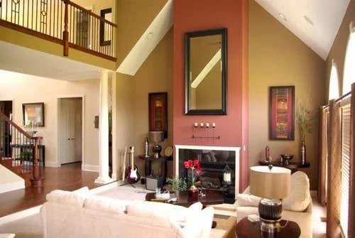 High-wall interior painting by Premier Painting and Design Inc. in Collinsville, Illinois. The image shows warm accent walls, white columns, a fireplace, and arched windows.