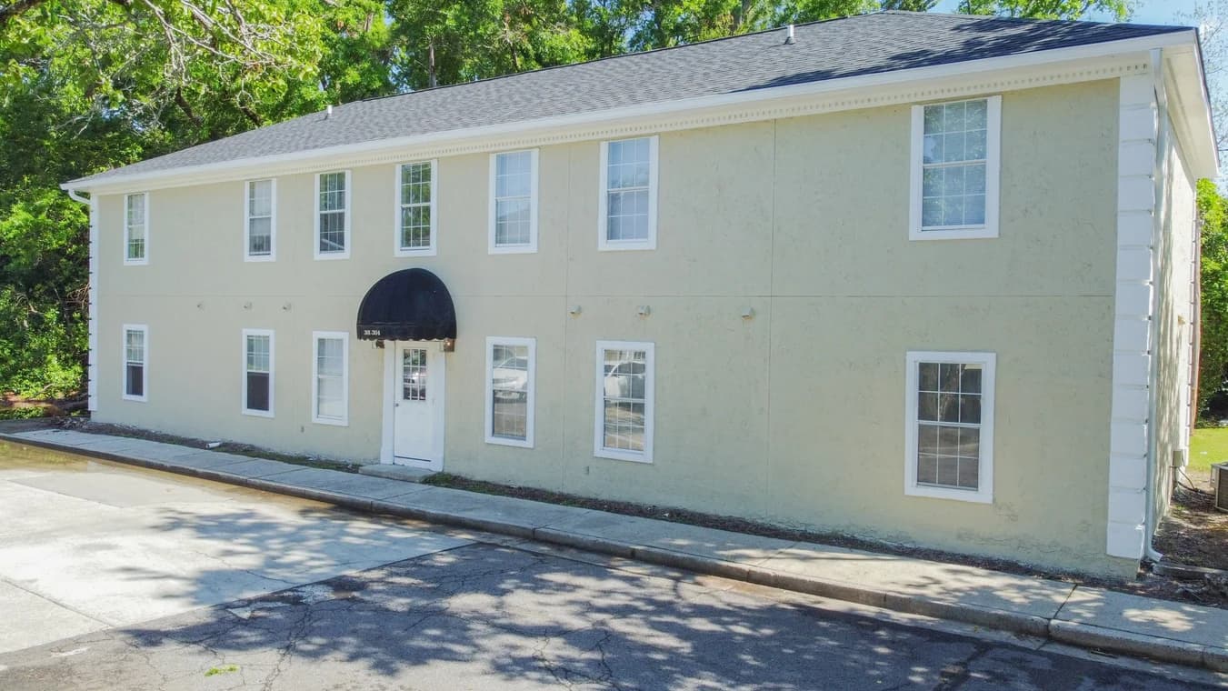 This is an image from A Cut Above Painting Co. company, located in Evans, GA The image is a two-story commercial building with beige stucco exterior, white trim, black awning, and freshly painted facade