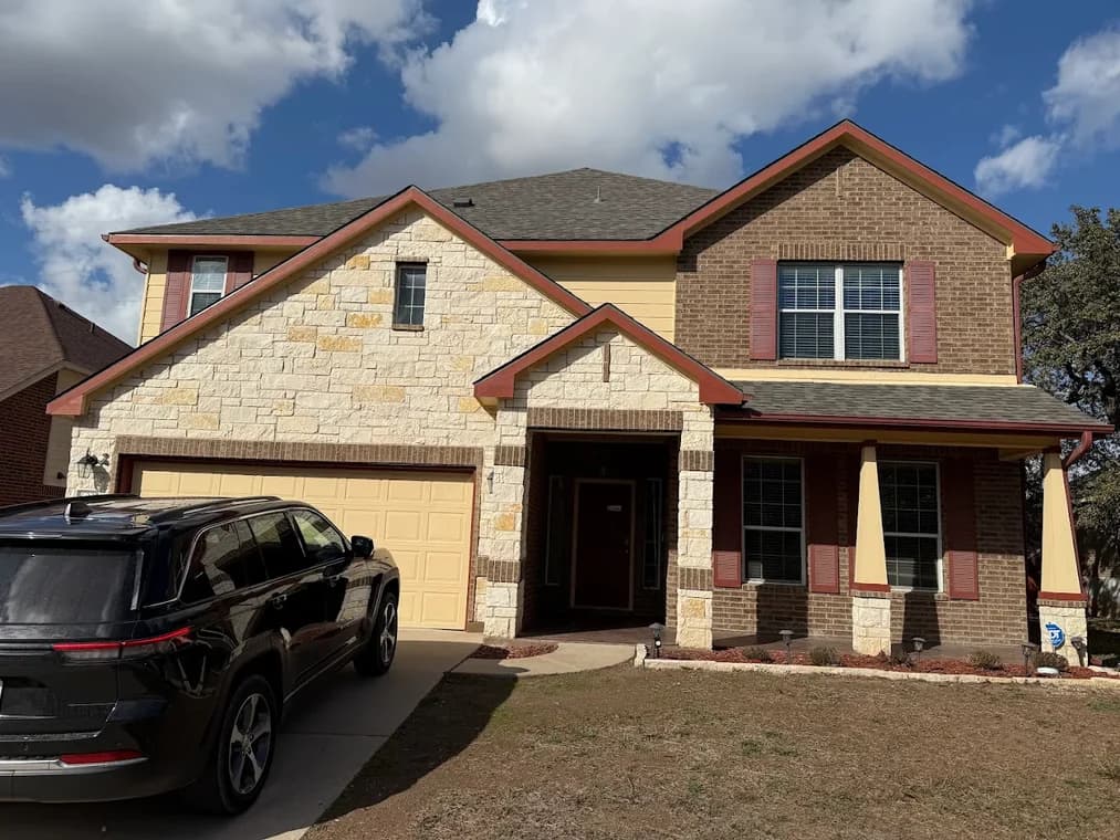 This is an image from Family Painting, located in Texas. The exterior photo shows a two-story home with painted siding, trim, and shutters complementing the stone and brick façade.