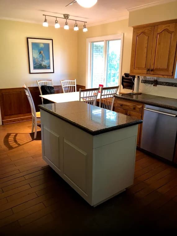 This is an image from A&L Painting, located in New York. The image shows a kitchen with a newly painted white island base contrasted with natural wood cabinets and flooring.