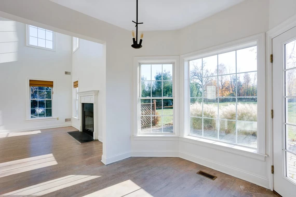 This is an image from KB Quality Painting, located in New York. The interior photo displays a bright room with newly painted white walls, tall windows, and natural light filling the space.