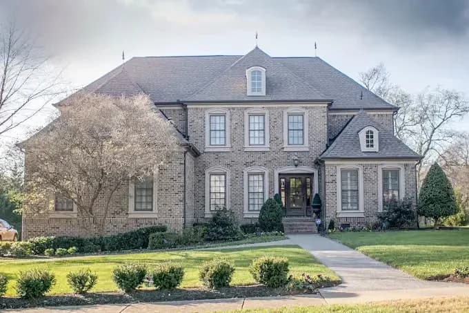 Painting project by Hisway Painting in Franklin, Tennessee. The image shows a stone two-story home with dark trim.