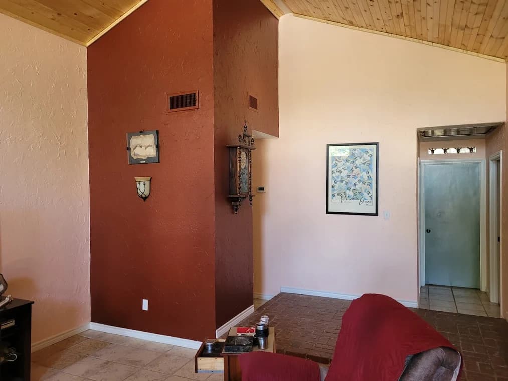 "This is an image from Hutch-N-Son Painting & Drywall, located in Texas. The interior view shows textured walls painted in contrasting peach and rust colors beneath a wood-paneled ceiling."