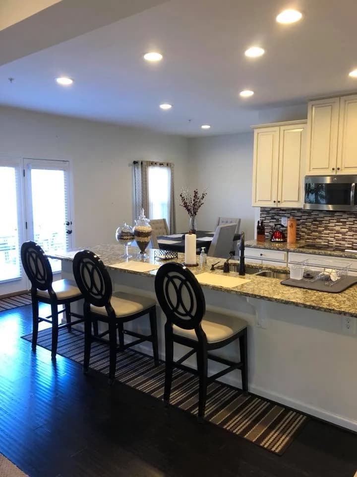 This is an image from Goode Design Painting & Wallcovering Inc., located in Virginia. The interior view features a modern kitchen with white cabinets, granite countertops, and recessed lighting.